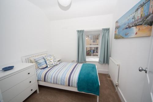 a small bedroom with a bed and a window at Polly Cottage in Teignmouth