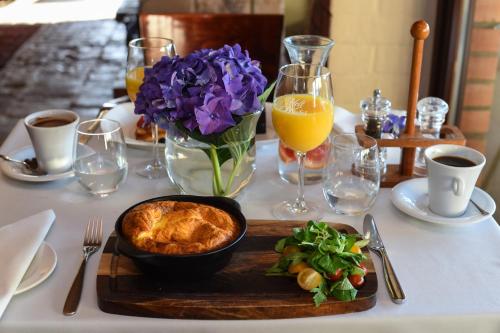 a table with a plate of food and a vase of purple flowers at Romantic Boutique Hotel & Spa in Panevėžys