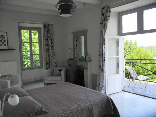 1 dormitorio con cama, chimenea y balcón en Le Prieuré, en Lézigné