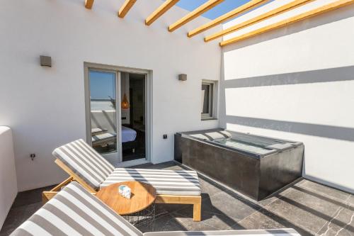 a room with a hot tub and two chairs at Aegean Gem in Kamari