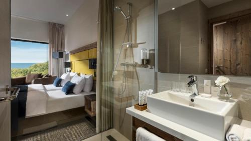 a bathroom with a sink and a shower and a bedroom at Hotel Sopot in Sopot