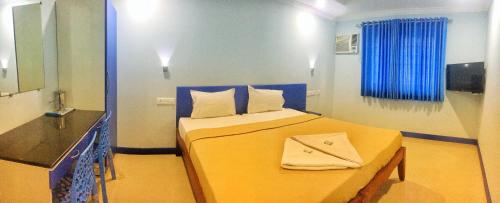 a bedroom with a yellow bed with a mirror and a sink at Kalluvalappil Holiday Inn in Kāsaragod