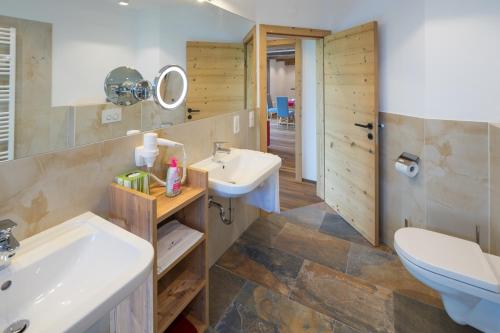 a bathroom with two sinks and a toilet and a mirror at Das Hillside Maria Alm Hintermoos in Maria Alm am Steinernen Meer