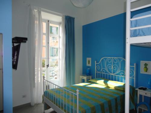 een blauwe slaapkamer met een bed en een raam bij L'alberghetto Milazzo in Milazzo