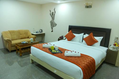 a bedroom with a bed with a chair and a table at Athena Hotel in Tiruvannāmalai