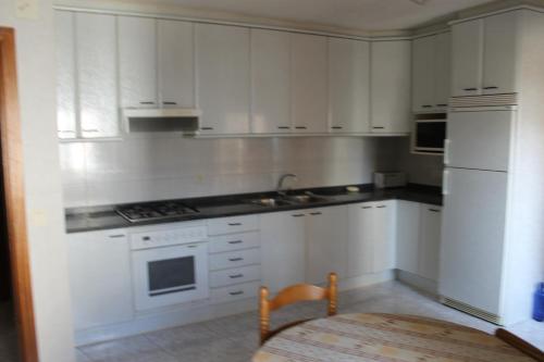 a kitchen with white cabinets and a table in it at Casa Miguel in La Portellada