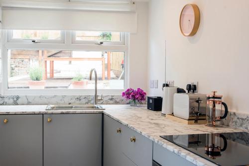 a kitchen with white cabinets and a sink and a window at Cornish Cottage - Truro City Centre in Truro