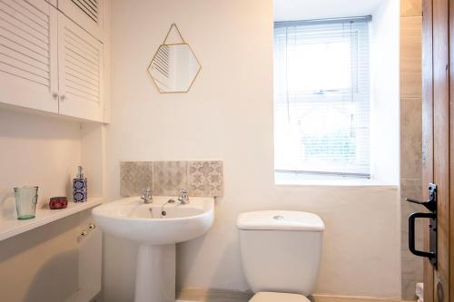 a bathroom with a white toilet and a sink at Cornish Cottage - Truro City Centre in Truro