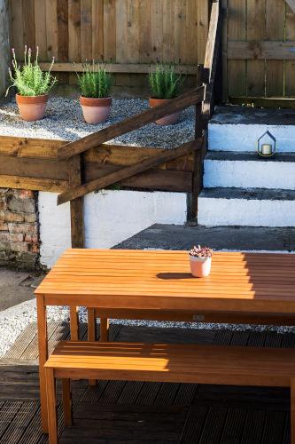 a wooden bench sitting next to some potted plants at Cornish Cottage - Truro City Centre in Truro