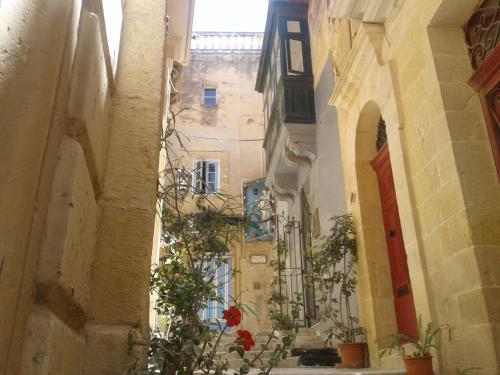 an alley in an old town with buildings and flowers at townhouse cospicua , ( 3 cities-valletta ) ferry in Cospicua