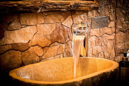a sink in a stone bathroom with a water fountain at Hotel Tejera del Nalon in Soto del Barco
