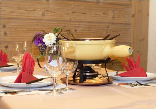 a table with a pot on a table with wine glasses at Hotel Restaurant Schönau in Wildhaus