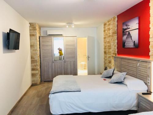 um quarto com uma cama grande e uma parede vermelha em Hôtel Terranostra em Tarascon-sur-Ariège