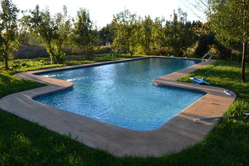 una piscina en un campo de césped con árboles en La Casa de Adobe Natural y Más, en Bulnes