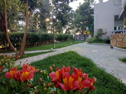a garden with red and yellow flowers and a sidewalk at BLEU- VERT in Prinos