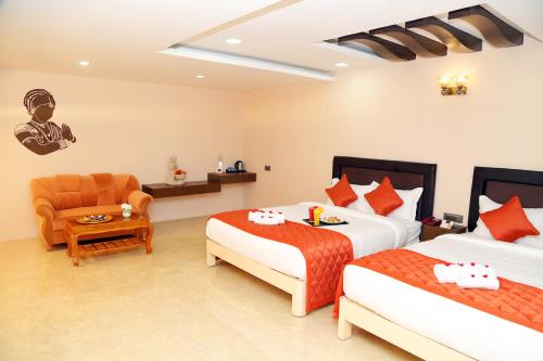 a hotel room with two beds and a chair at Athena Hotel in Tiruvannāmalai