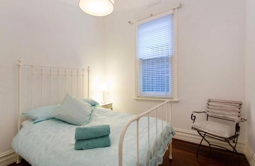 a bedroom with a bed and a chair and a window at Gorgeous Subiaco cottage in Perth
