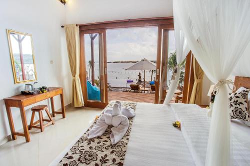 a room with a bed, a table and a window at Nusa Veranda Sunset Villas & Restaurant in Nusa Lembongan
