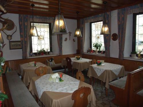 ein Esszimmer mit Tischen, Stühlen und Fenstern in der Unterkunft Gasthof Alte Post in Obertrubach
