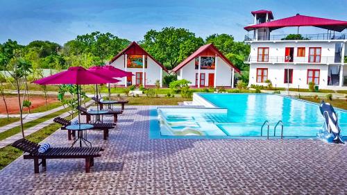 un complejo con piscina, mesas y sombrillas en Santon Resort & Spa - Level 1 Certified, en Tangalle
