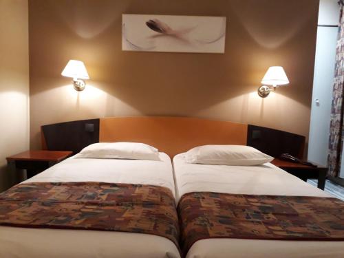 a hotel room with two beds and two lamps at Logis Le Relais de Fusies in Lacaune