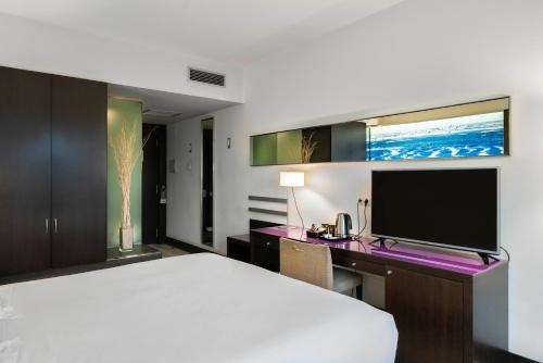 a bedroom with a bed and a desk with a television at Vincci Maritimo in Barcelona