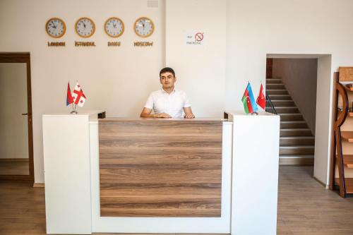 a man sitting at a reception desk in a room at Evim Otel in Zaqatala