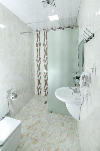 a white bathroom with a sink and a shower at Evim Otel in Zaqatala