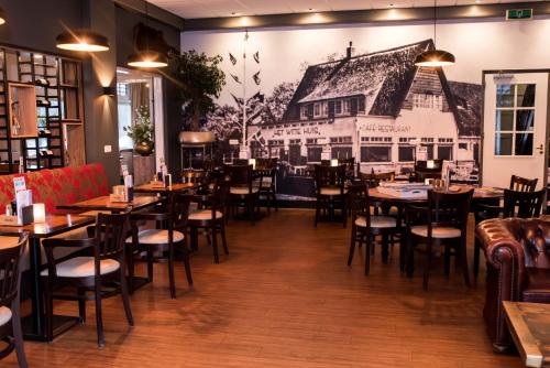 a restaurant with tables and chairs and a mural on the wall at Hotel Restaurant Het Witte Huis in Olterterp