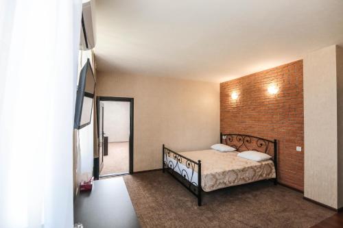 1 dormitorio con cama y pared de ladrillo en Evim Otel, en Zaqatala