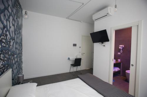 een slaapkamer met een bed en een tv aan de muur bij Caicco suite in Margherita di Savoia