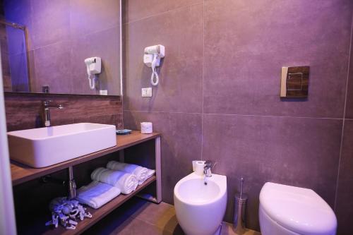 een badkamer met een wastafel, een toilet en een spiegel bij Caicco suite in Margherita di Savoia