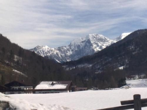 una cordillera cubierta de nieve con un edificio en el primer plano en Alpenpension Auengrund, en Ramsau