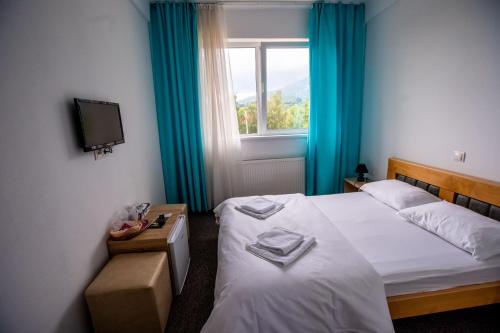 a hotel room with two beds and a window at Pensiune Perla - Bistrița Năsăud in Susenii Bîrgăului