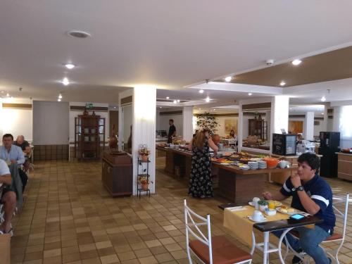 a group of people sitting at tables in a restaurant at Barreto Apart-hotel Kubit in Brasilia