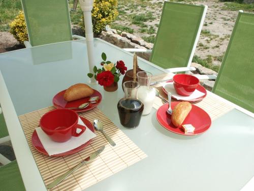 una mesa con platos y tazas rojos y comida en ella en Les Chambres d'Helix en Saint-Dizier-les-Domaines