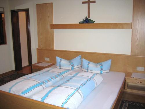 1 cama con almohadas azules y una cruz en la pared en Haus Hubert, en Arzl im Pitztal