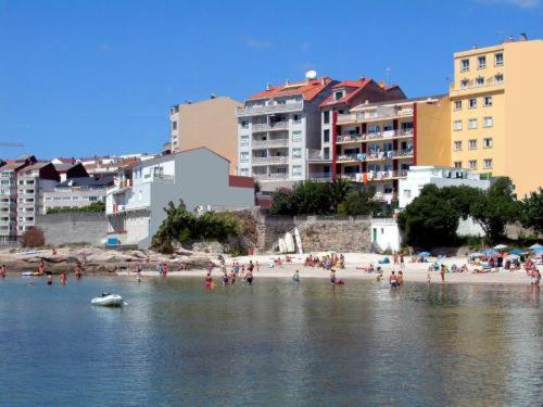 un grupo de personas en una playa en el agua en Hotel El Puente, en Sanxenxo