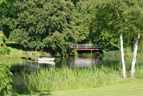 a bench on a bridge over a river with a boat at Rønhave in Sønderborg