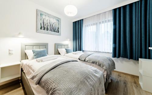 カルパチにあるApartamenty Sun & Snow Sarnia Residenceの青いカーテン付きのベッドルームのベッド2台