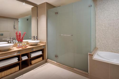 a bathroom with two sinks and a shower at Mövenpick Resort & Spa Tala Bay Aqaba in Aqaba