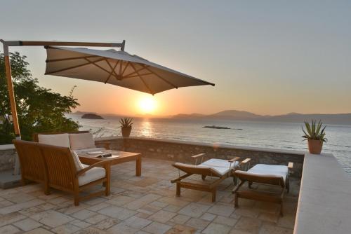 a patio with a table and chairs and an umbrella at Hydra Kamini Beach Thea in Hydra