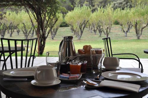 a table with plates and cups and a tea kettle at Le Jardin des Amandiers in Châteaurenard