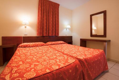 Schlafzimmer mit einem Bett mit einer roten Bettdecke und einem Spiegel in der Unterkunft Blue Sea Jandia Luz in Morro del Jable