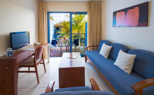 a living room with a blue couch and a tv at BLUESEA Jandia Luz in Morro del Jable