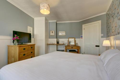 a bedroom with a white bed and a television at Exmoor House in Wheddon Cross