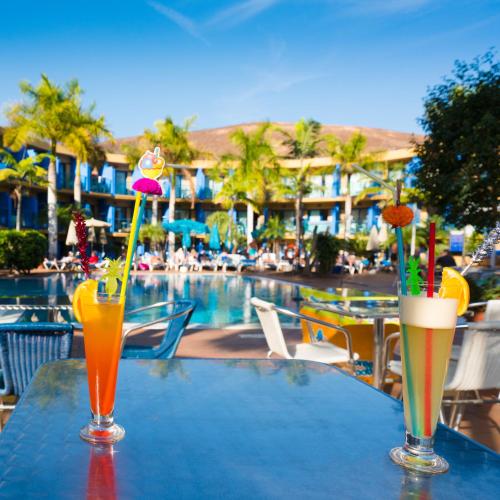 two drinks on a table next to a swimming pool at BLUESEA Jandia Luz in Morro del Jable