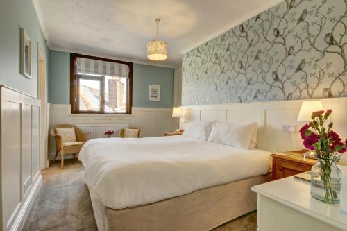 a bedroom with a large white bed and a window at Exmoor House in Wheddon Cross