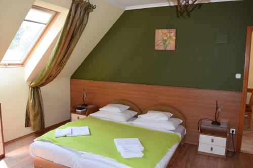 a bedroom with a bed with a green wall at Natural Panzió in Győr