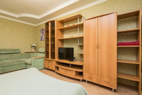 ニジニ・ノヴゴロドにあるHomeHotel Молодежный 38/2の木製キャビネットとテレビ付きのベッドルーム1室